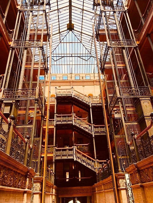 Interior atrium of the Bradbury Building with ornate ironwork, staircases, and glass skylight